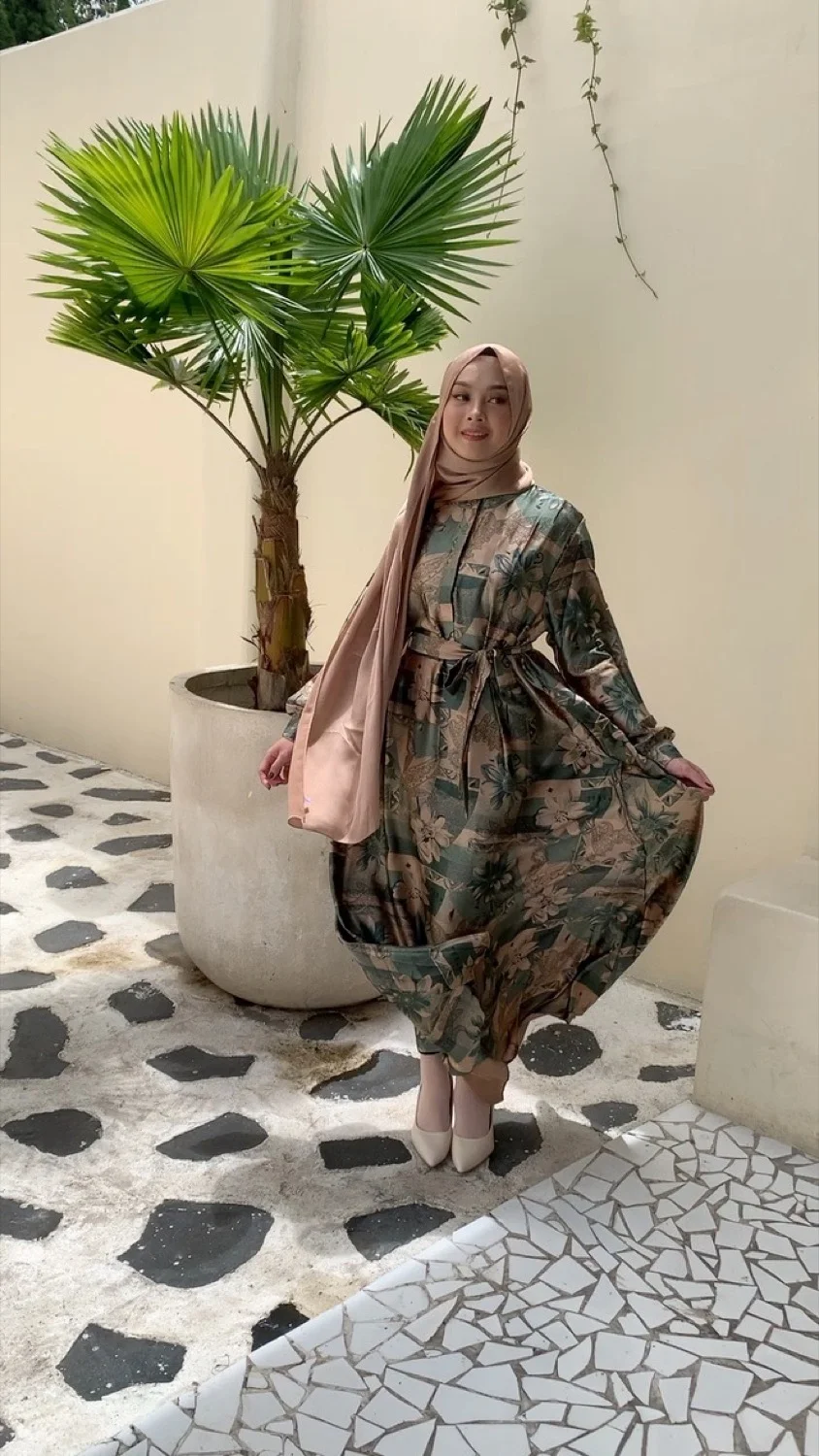 Model mengenakan gamis dengan motif tropis daun palem — tips mix and match busana muslim
