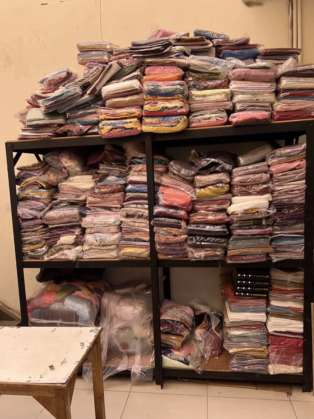 Rak penyimpanan stok hijab dan busana muslim warna-warni di gudang Tiga Raga Konveksi